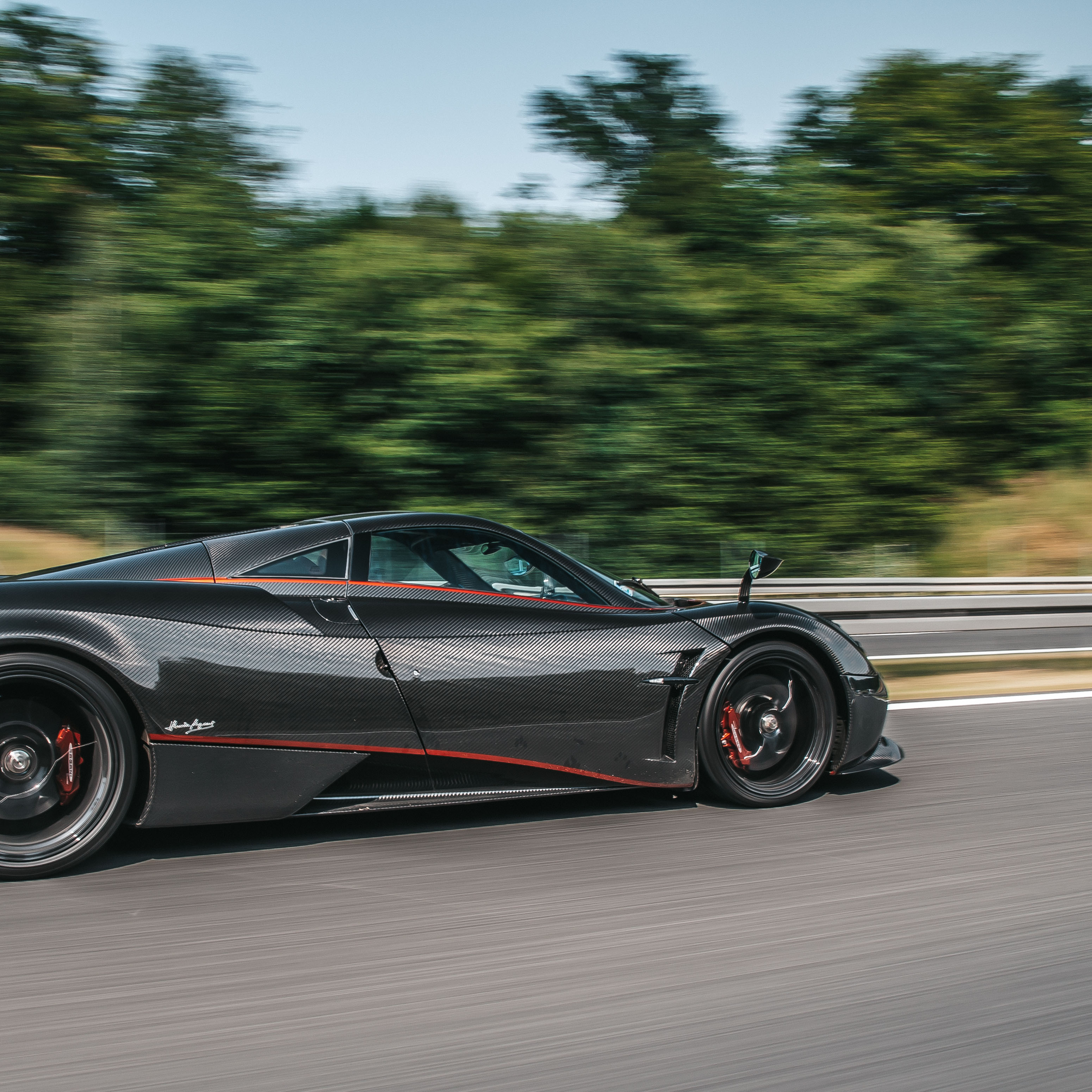 barber using styling spray on young man with black hair, short on sides and long in a quiff on top